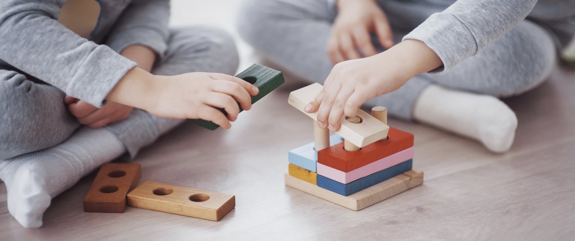 Dos niños armando un juego de encaje de madera con piezas de colores