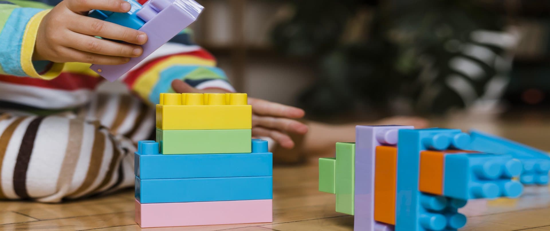 Niño apilando bloques de encaje de colores sobre una mesa de madera
