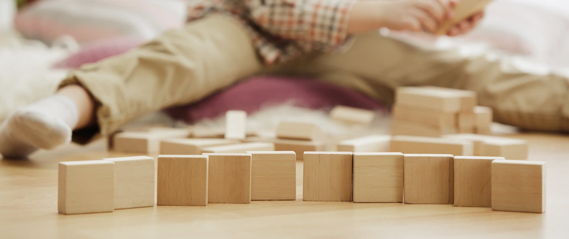 Niño jugando con cubos de madera natural ordenados en fila